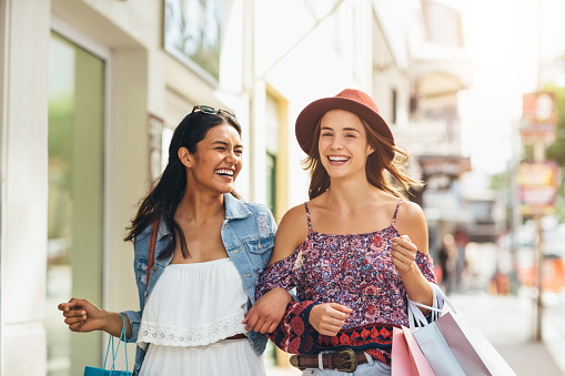 Two friends carrying shopping bags at an outdoor mall