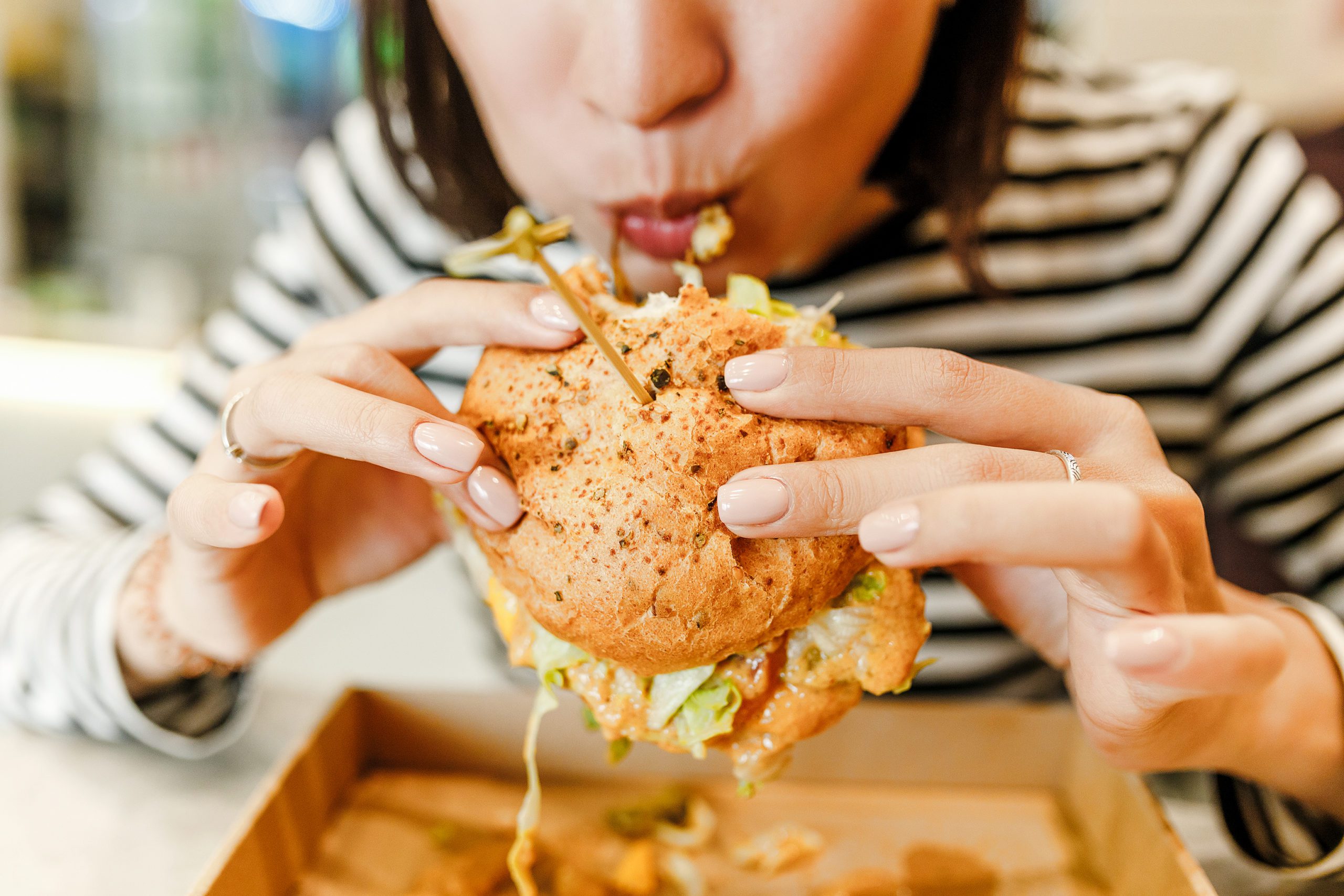 Close up of woman eating a hamburger in restaurant