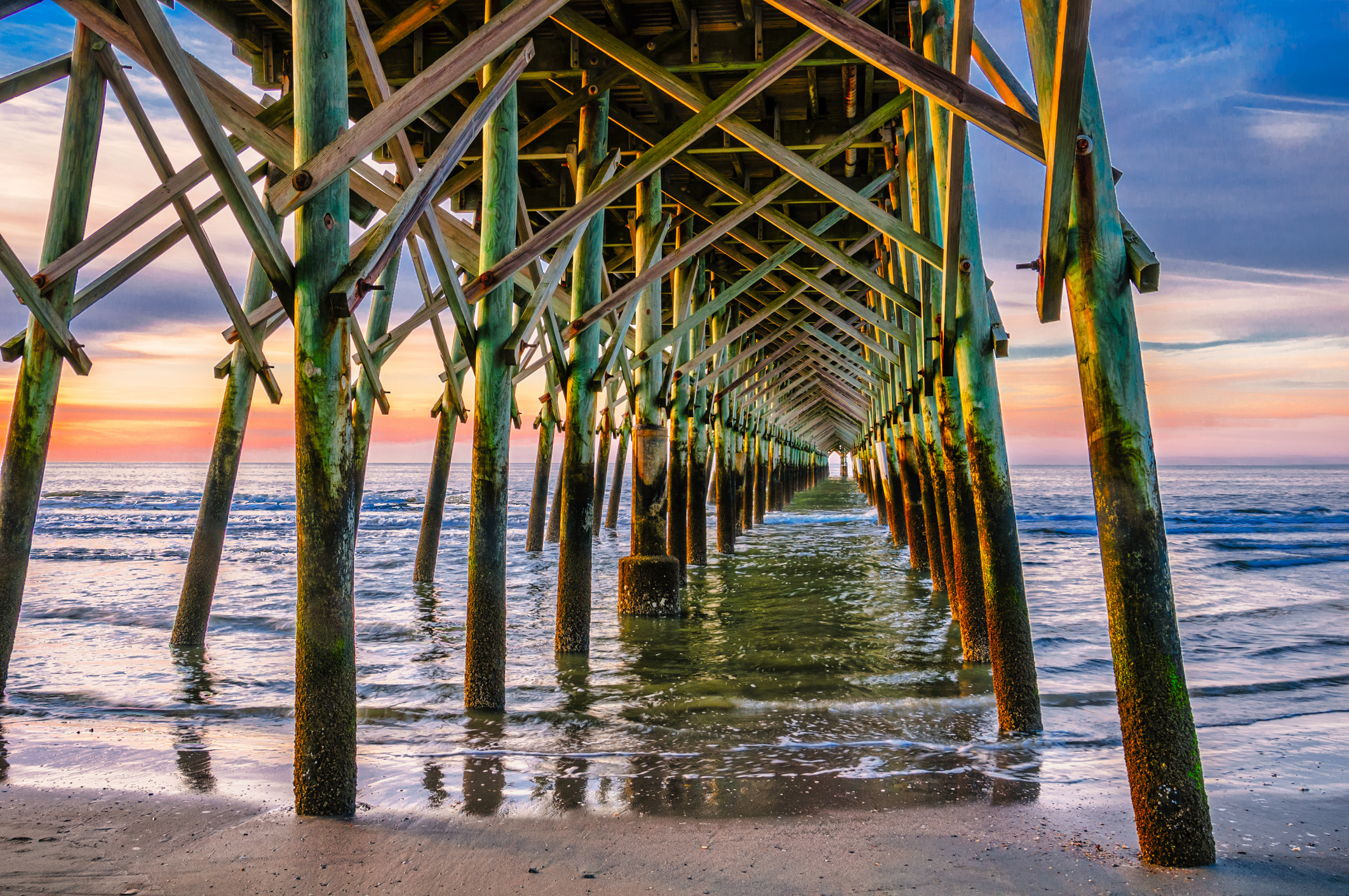 beneath a beach pier at sunrise