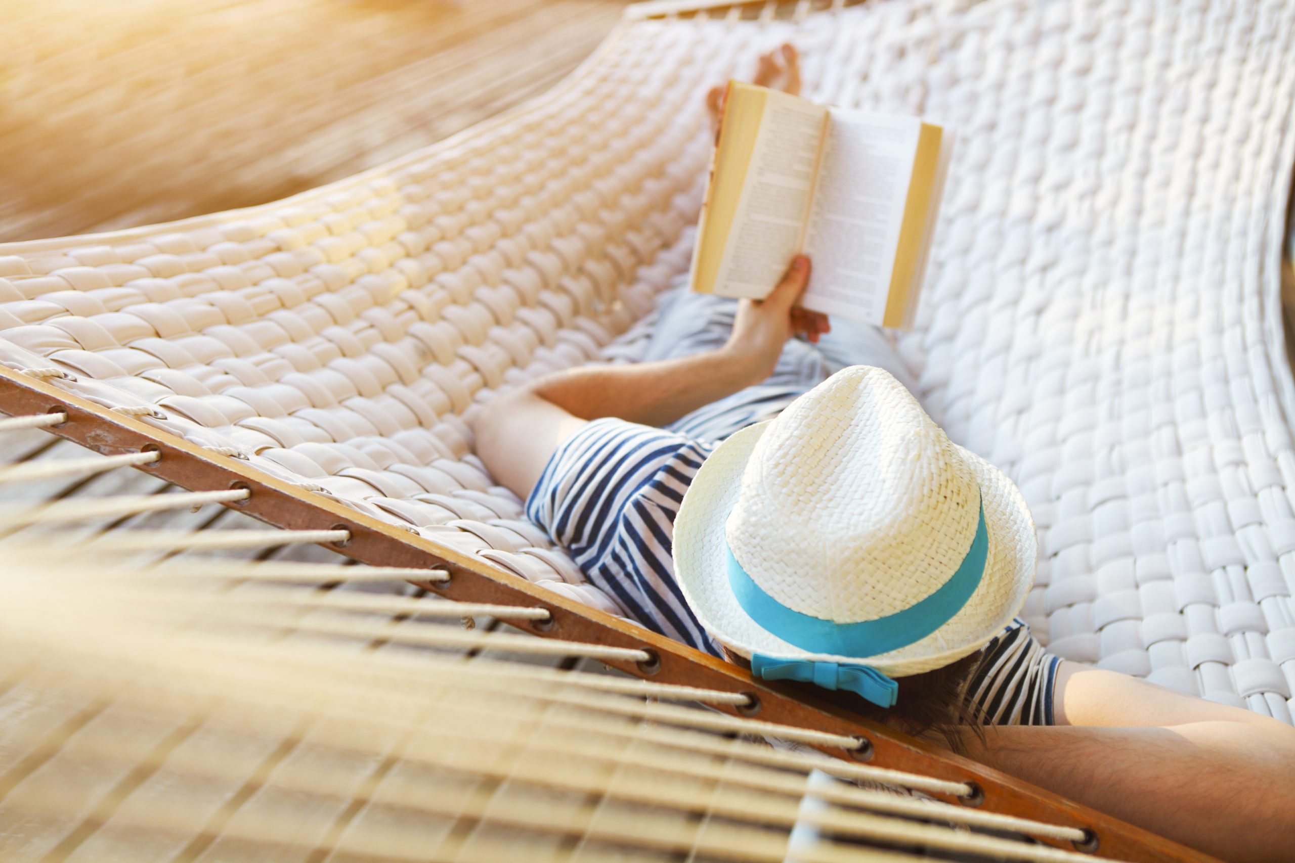 Man in a hammock with book on summer day