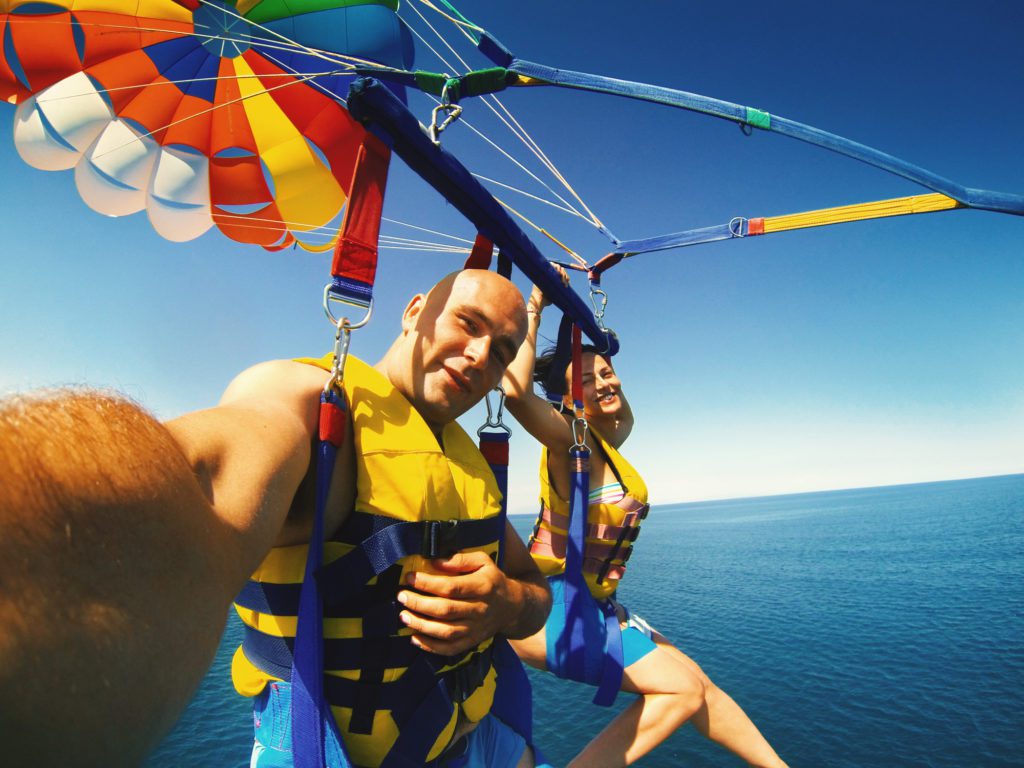 a couple parasailing over the ocean, one of the top myrtle beach watersports