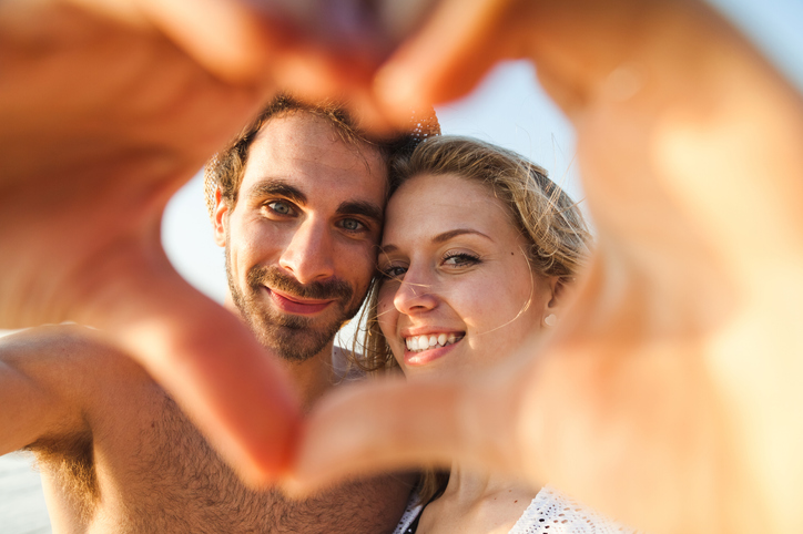 Loving couple on the beach seen through heart made with hands on myrtle beach honeymoon