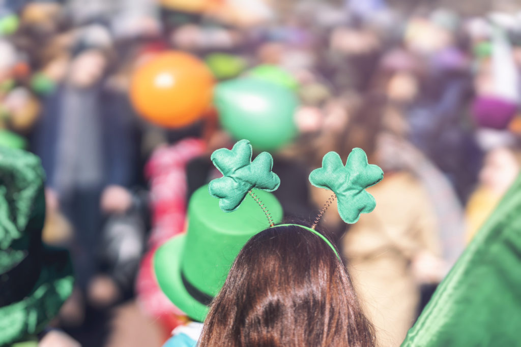 Clover head decoration on head of girl close-up. Saint Patrick day, parade in the city, selectriv focus